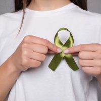 green-ribbon-symbol-of-kidney-cancer-isolated-on-gray-wall