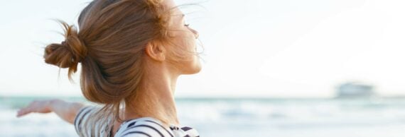 Accueil SYNLAB - Laboratoires d'analyses médicales - Femme ayant les bras écartés devant la mer