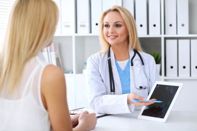 Un docteur qui montre l'écran de sa tablette à sa patiente